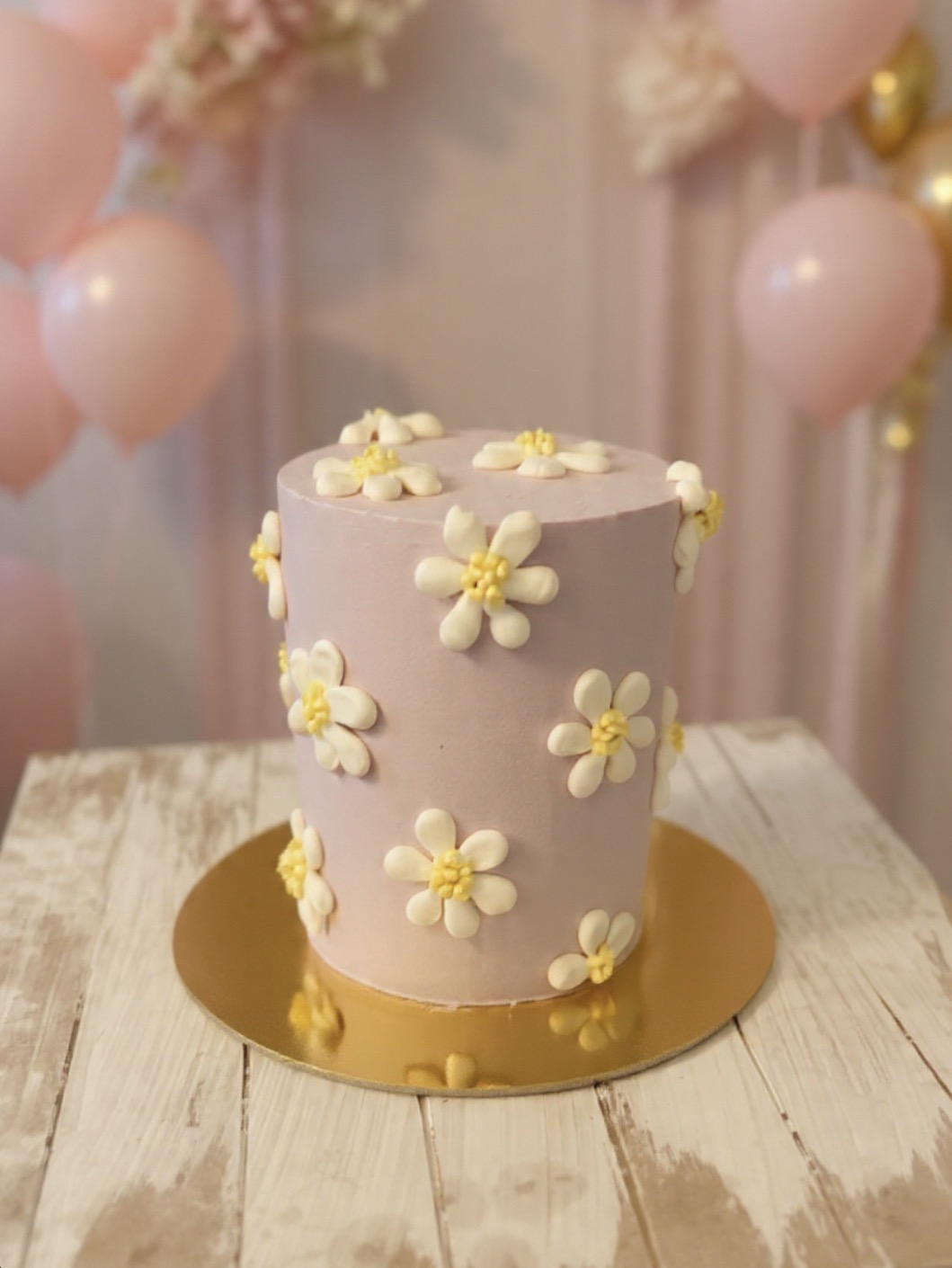 Blush daisy cake with soft pink balloon garland